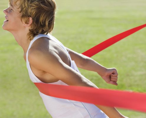 high school runner crossing the finish line first