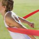 high school runner crossing the finish line first