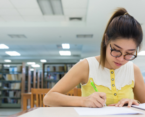 high school student writing an sat essay in the library